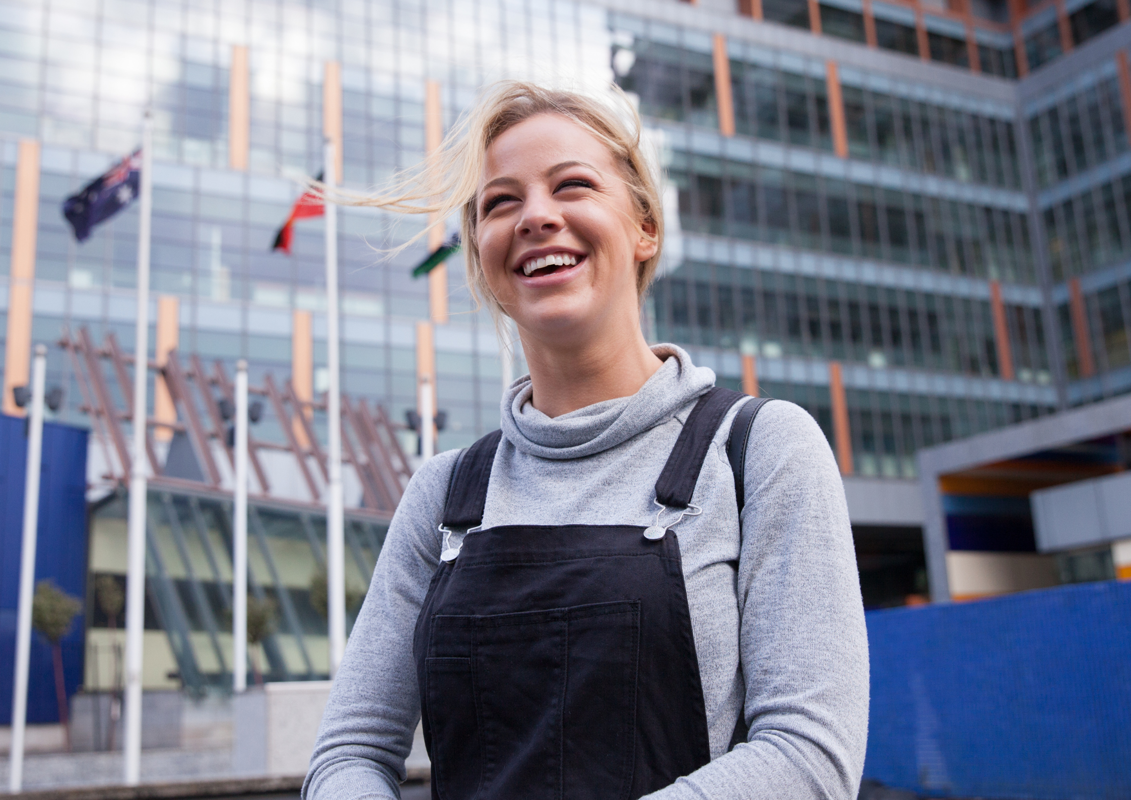 young woman smiling in front of a shiny office building